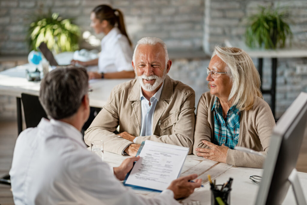 Happy mature couple talking to a doctor while going through their medical reports.